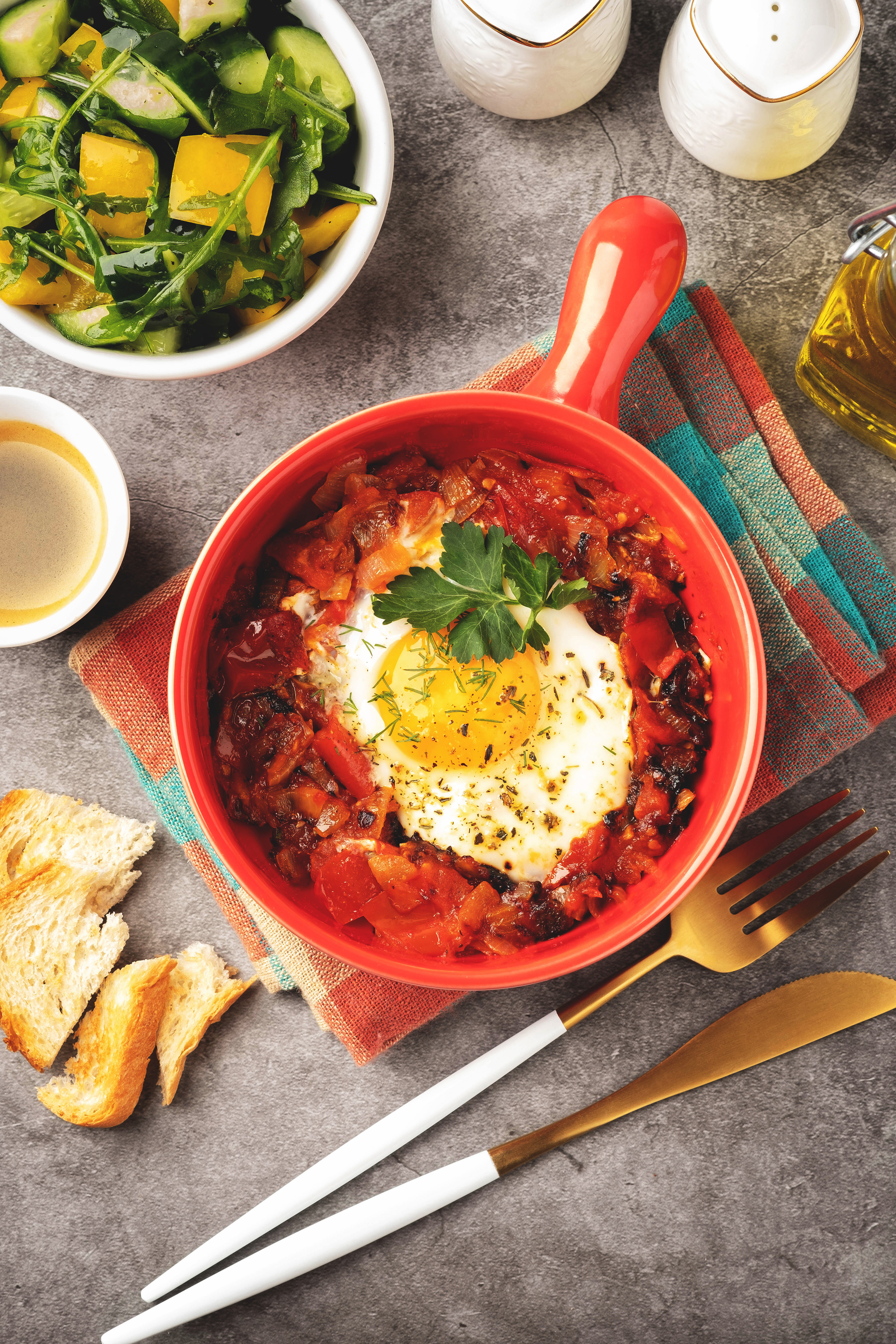 Overhead flat-lay of all ingredients for Spicy Tunisian Shakshuka with Merguez Sausage laid out on a kitchen surface.