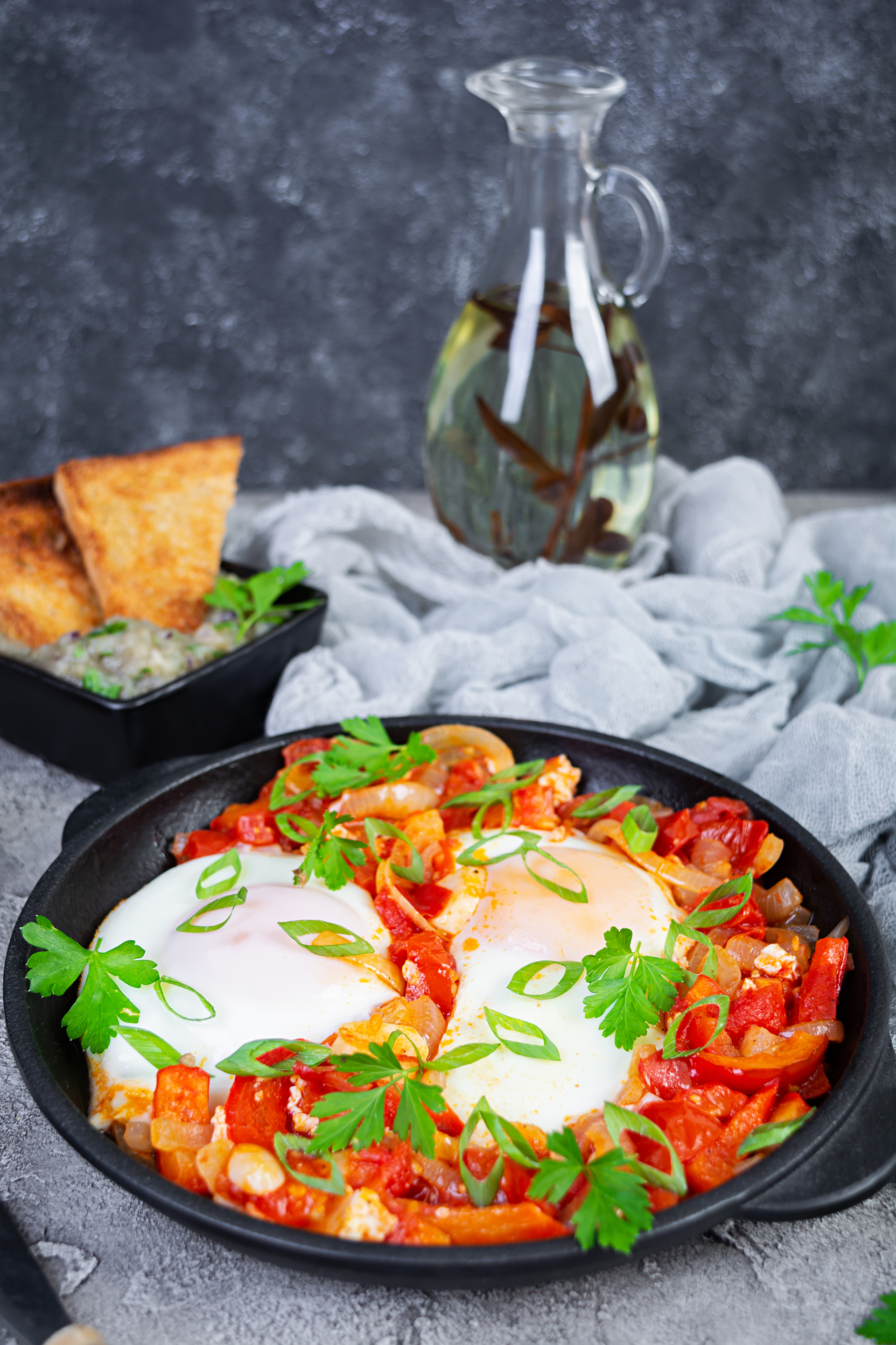 Overhead flat-lay of all ingredients for Sumptuous Israeli Shakshuka with Roasted Red Pepper and Feta laid out on a kitchen surface.
