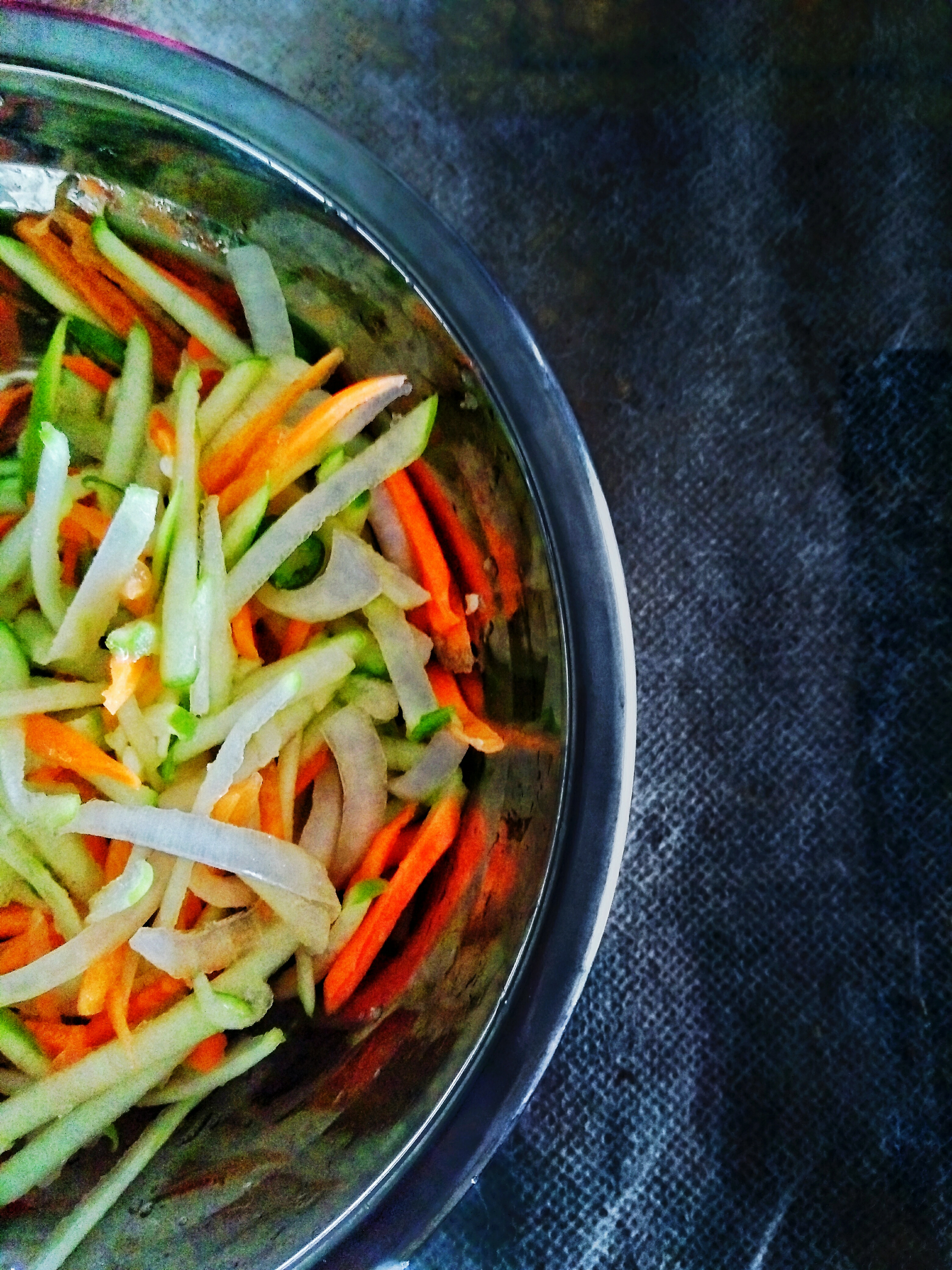 Overhead flat-lay of all ingredients for Tangy Korean Cucumber Kimchi Salad with Chili Flakes laid out on a kitchen surface.