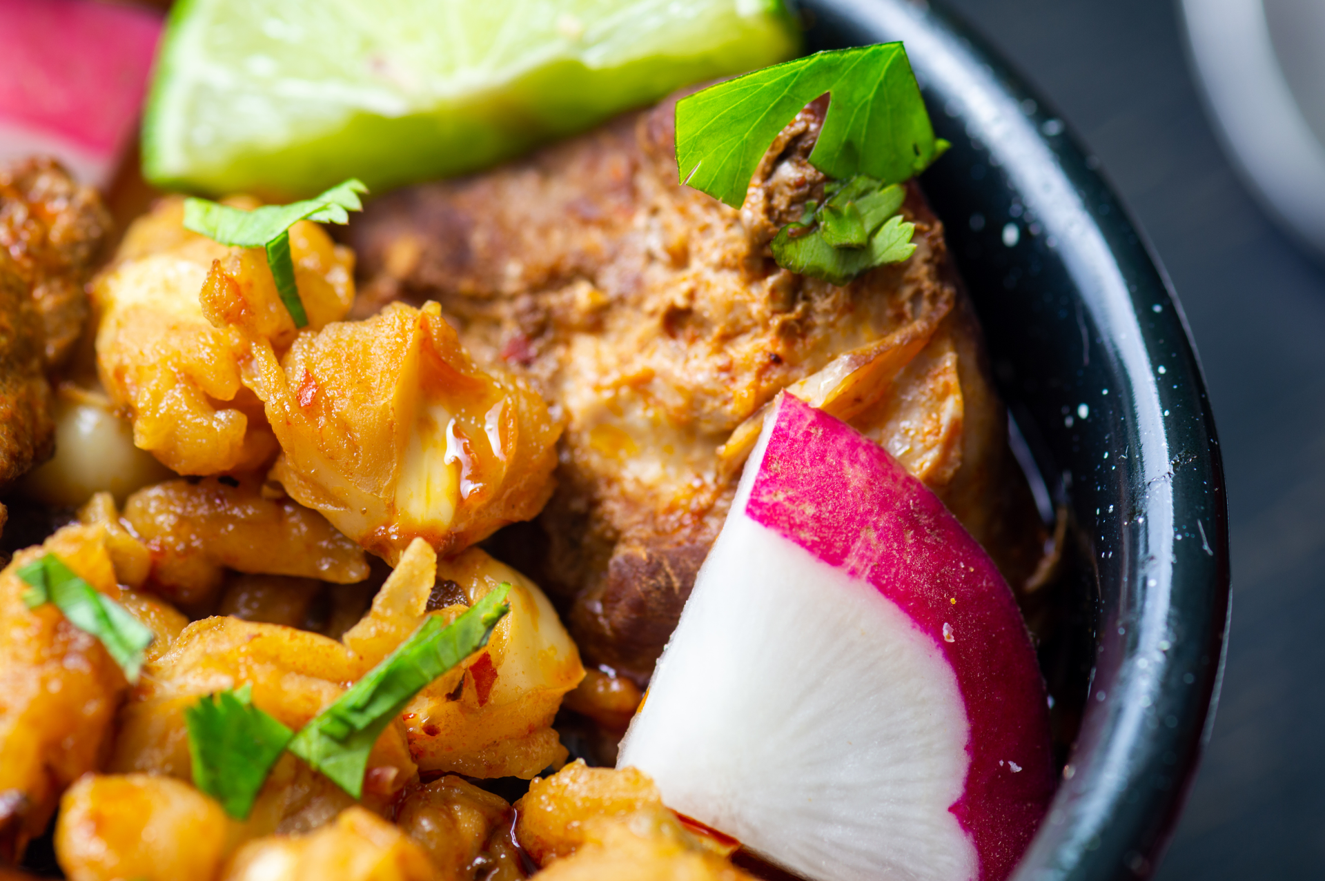 Overhead flat-lay of all ingredients for Tangy Nicaraguan Vigorón with Yuca and Crispy Pork Rinds laid out on a kitchen surface.
