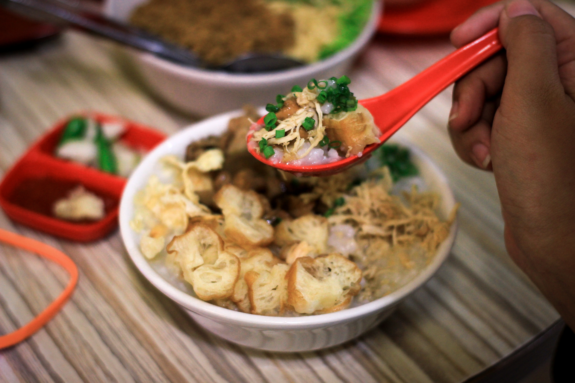 Overhead flat-lay of all ingredients for Traditional Indonesian Bubur Ayam with Shredded Chicken Satay laid out on a kitchen surface.