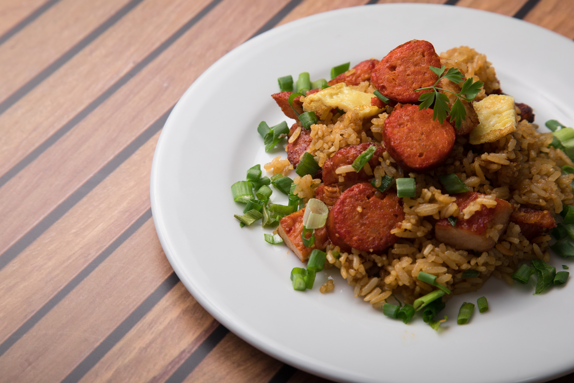 Overhead flat-lay of all ingredients for Vegan Nigerian Jollof Rice with Plant-Based Sausages laid out on a kitchen surface.