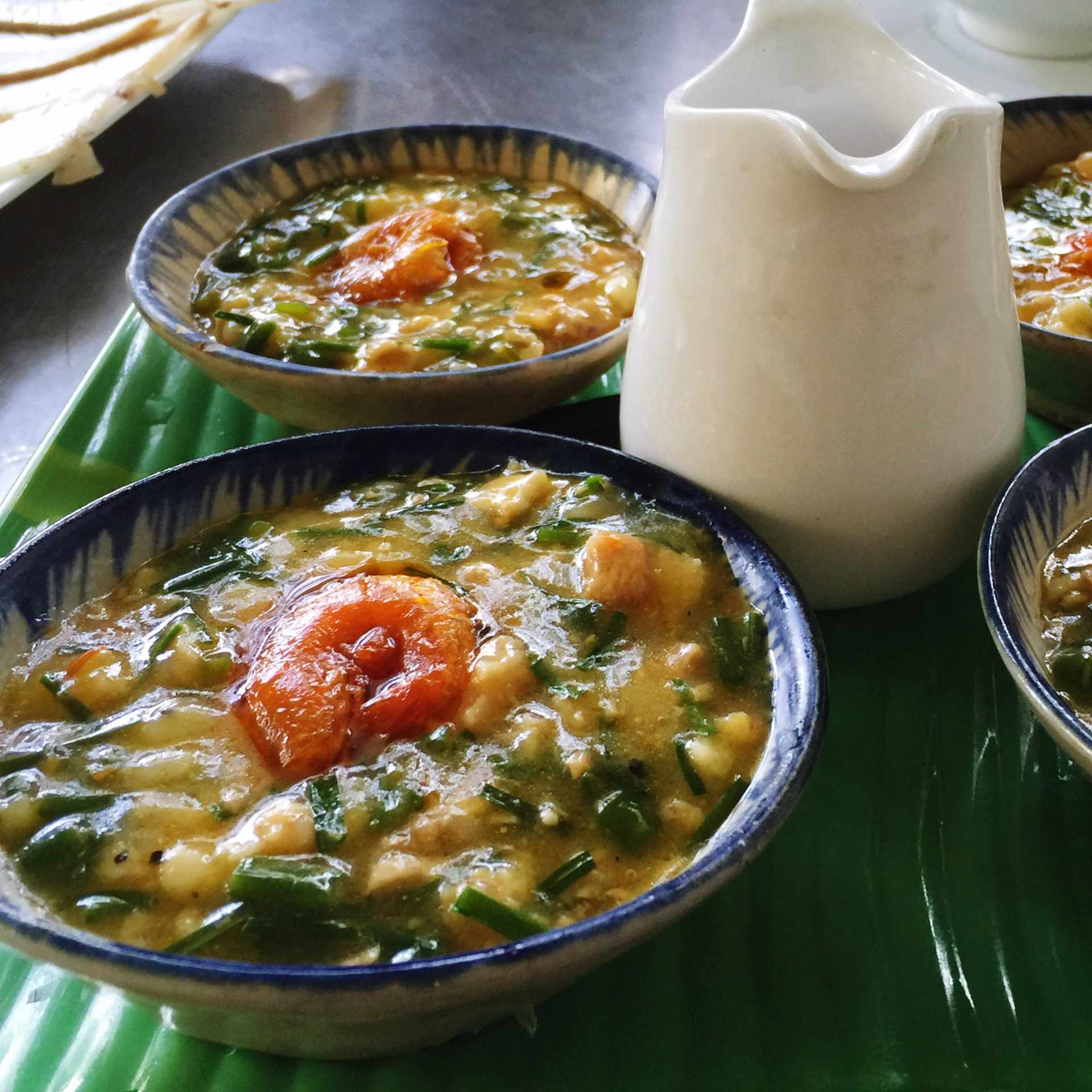 Overhead flat-lay of all ingredients for Venezuelan Hallaca Soup with Plantain Dumplings laid out on a kitchen surface.
