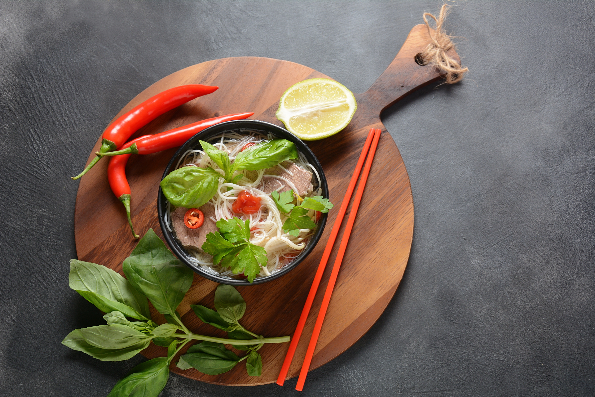 Overhead flat-lay of all ingredients for Vietnamese Pho Ga with Vietnamese Coriander and Lime laid out on a kitchen surface.