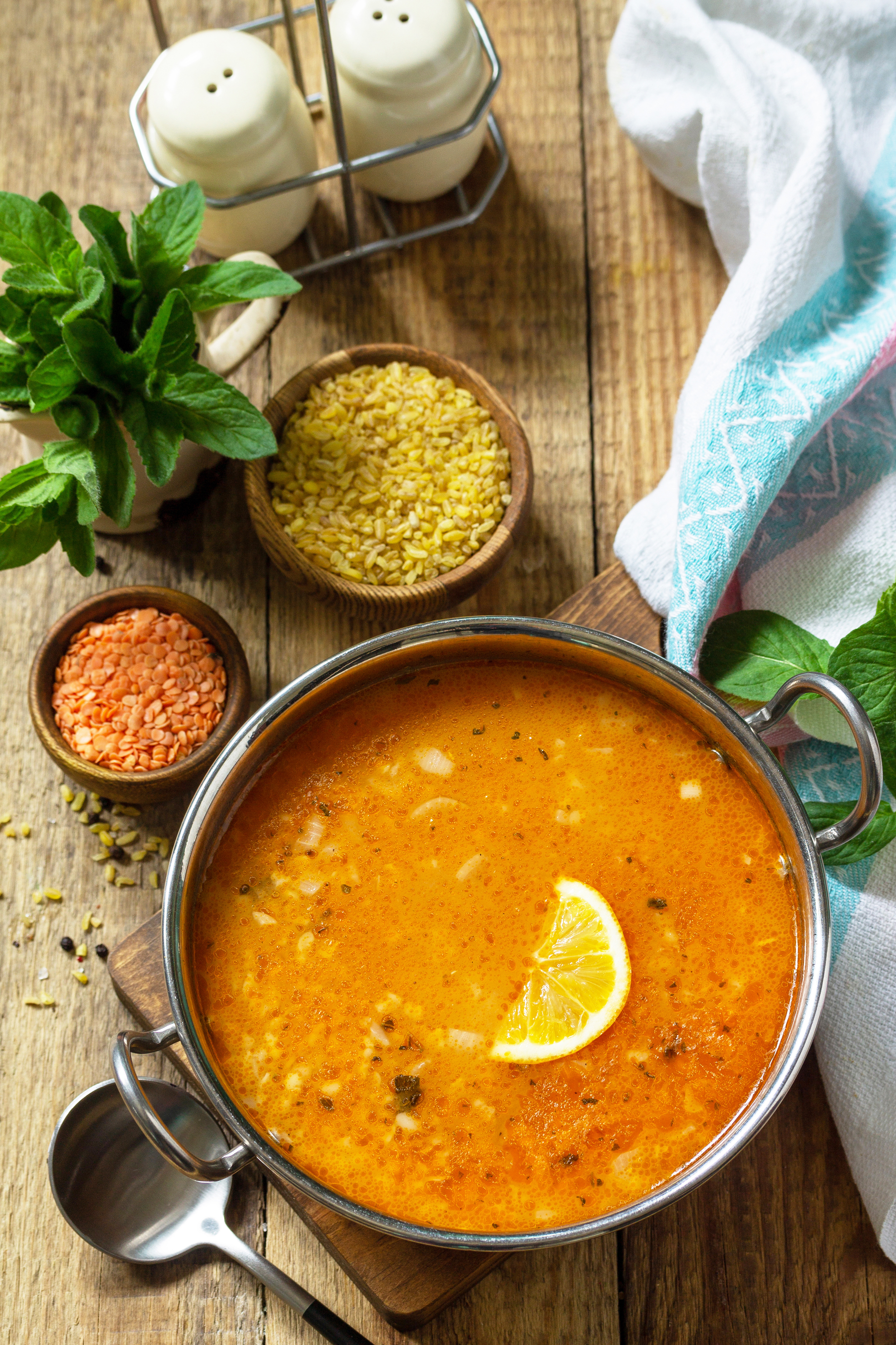 Overhead flat-lay of all ingredients for Zesty Armenian Lentil Soup with Sumac and Fresh Herbs laid out on a kitchen surface.