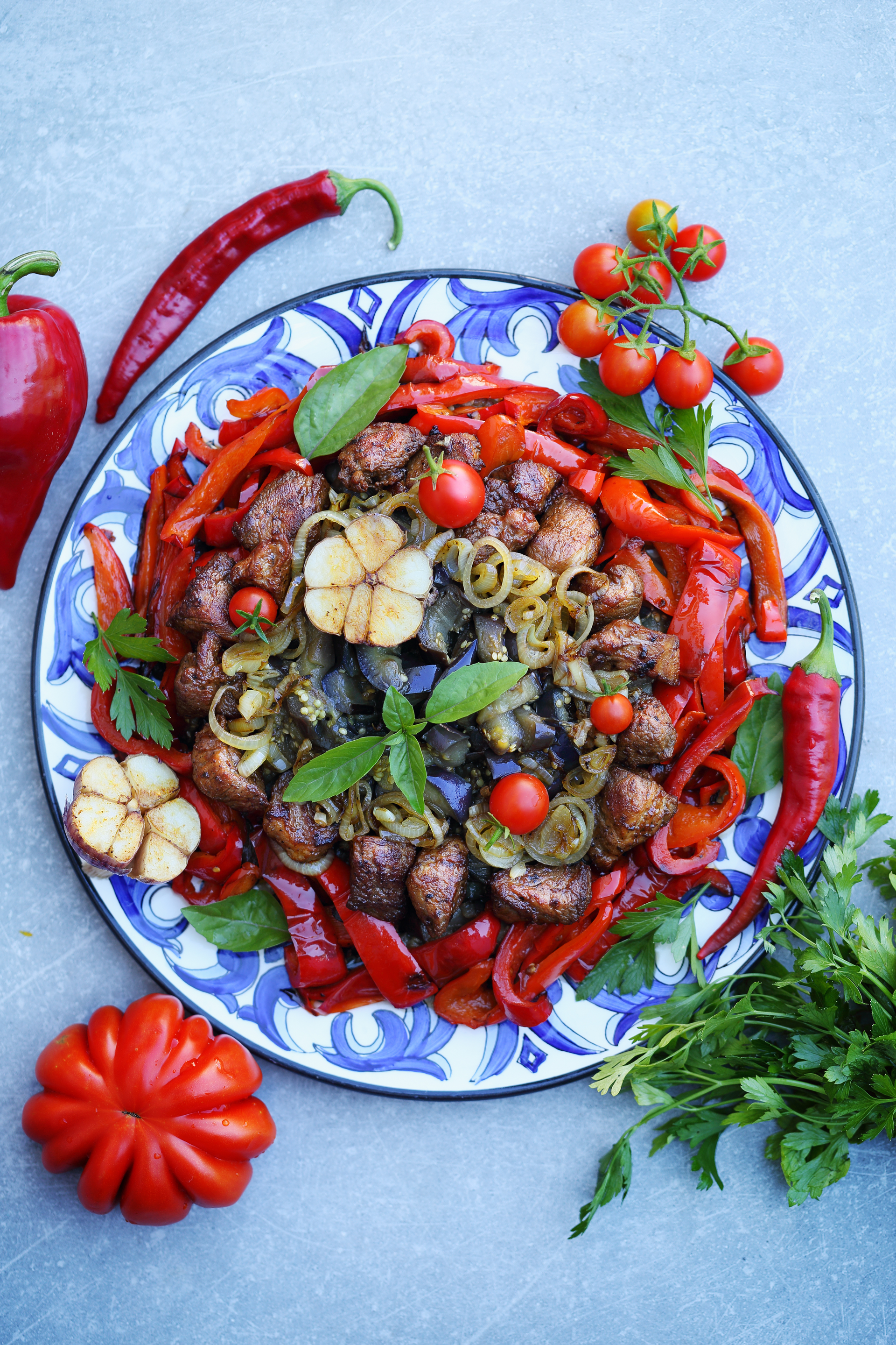 Overhead flat-lay of all ingredients for Zesty Tunisian Grilled Pepper Salad laid out on a kitchen surface.